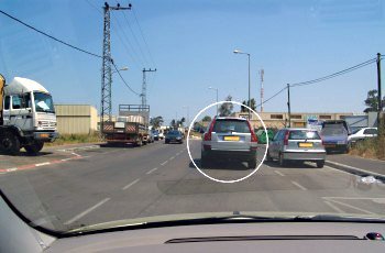 נתיב נסיעתך נחסם על ידי הרכב הכסוף החונה בחנייה כפולה (מסומן בעיגול). מה עליך לעשות?